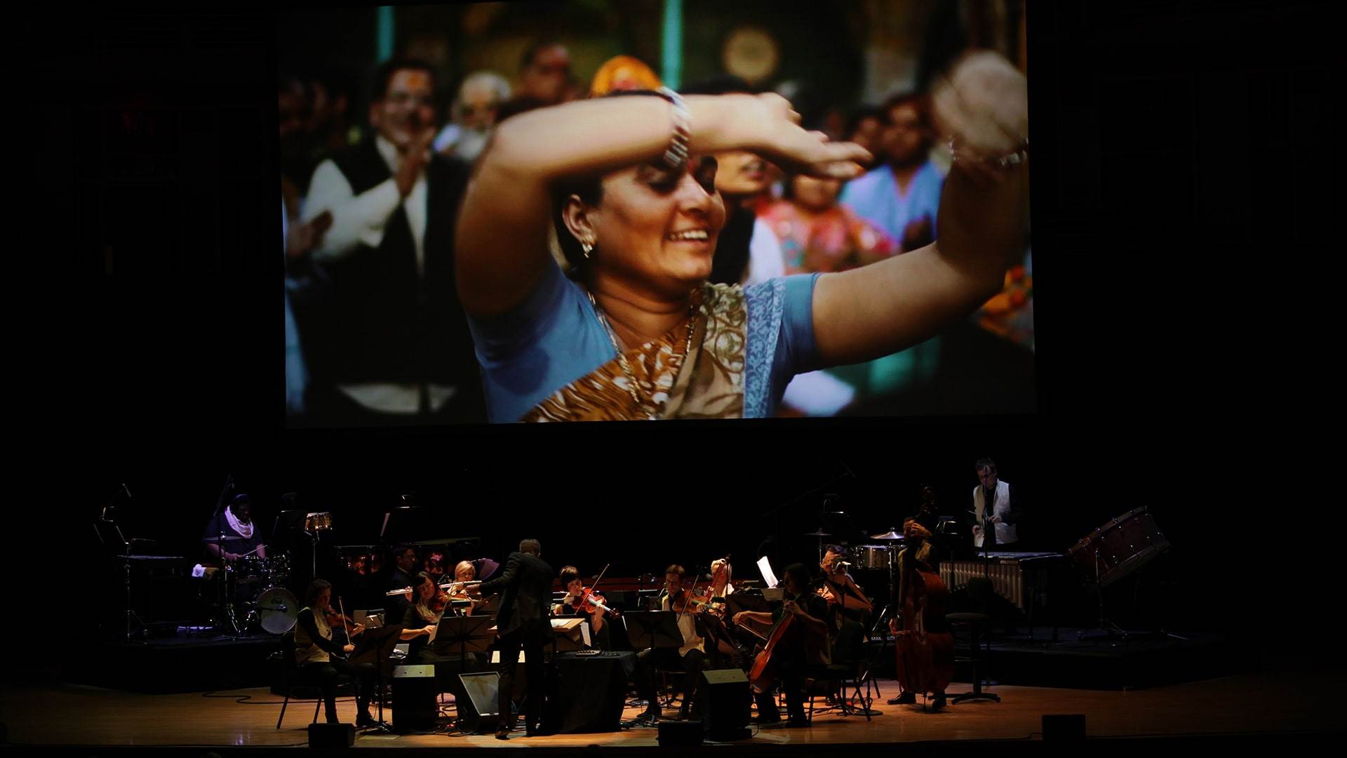 Muscians On Stage With Movie Screen Above Them In Radhe Radhe At Strathmore 1920X1080