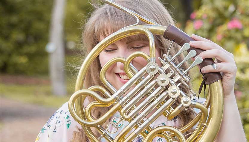 Caiti Beth Mckinney Smiling And Holding A Horn