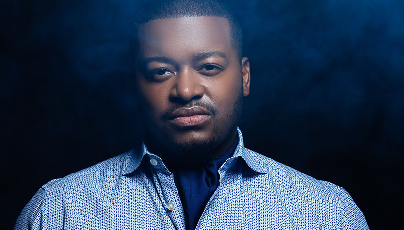 Dante Pope In A Blue Check Shirt Against A Black Background Cropped