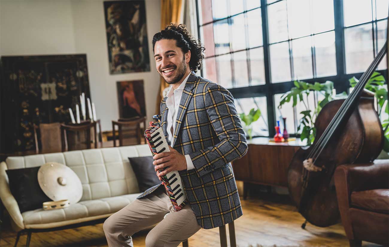 Emmet Cohen In A Plaid Blazer Surrounded By Instruments