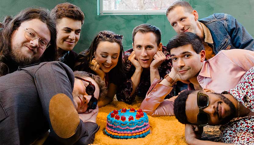 Strutman Lane Band Members Leaning On A Table Surrounding A Cake