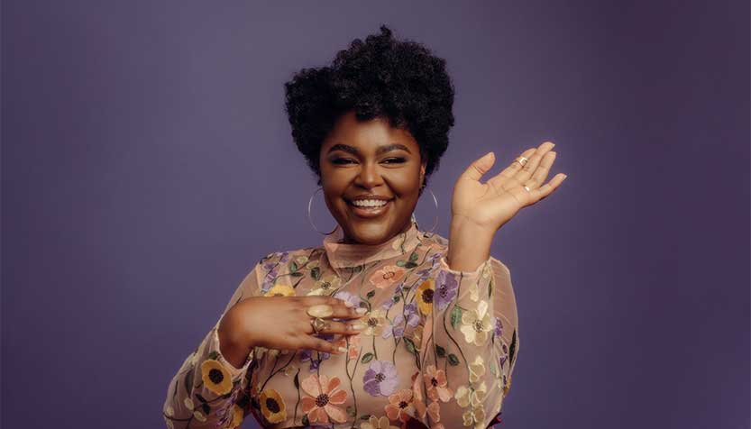 Christie Dashiell In A Beige Floral Dress Against A Purple Background