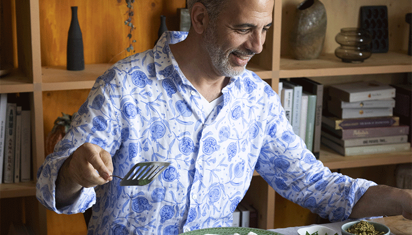 Yotam Ottolenghi Wearing A Patterned Blue And White Shirt Seated At A Table Full Of Food