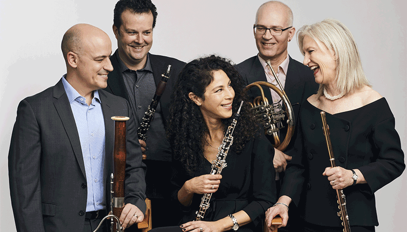 Dorian Wind Quintet Holding Their Instruments And Smiling At Each Other