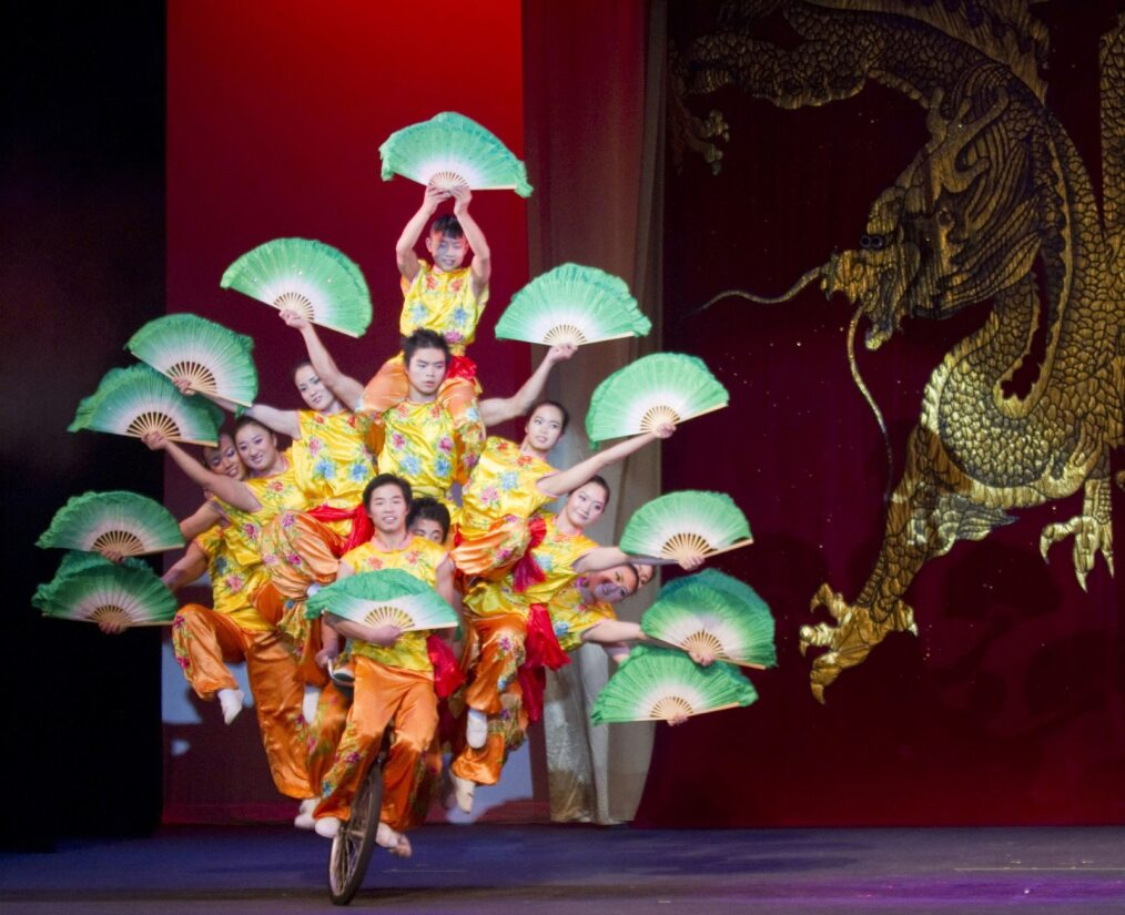 Peking Acrobats Stacked On A Single Bicycle With Unfurled Fans