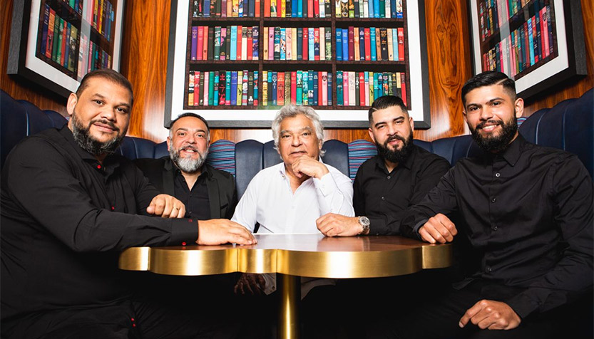 Gipsy Kings Seated At A Table Surrounded By Books